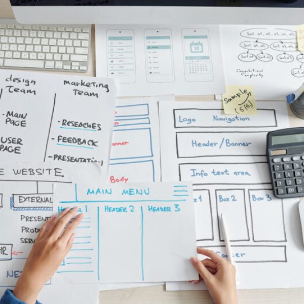 Project manager looking at drawings created by UI and UX designers and marketing department for new mobile application of company